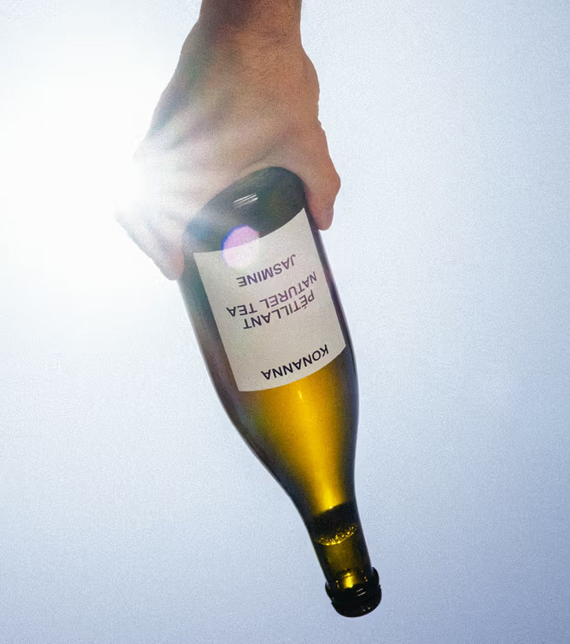 Bottle of Konana wine held by a hand against a light background moodshot