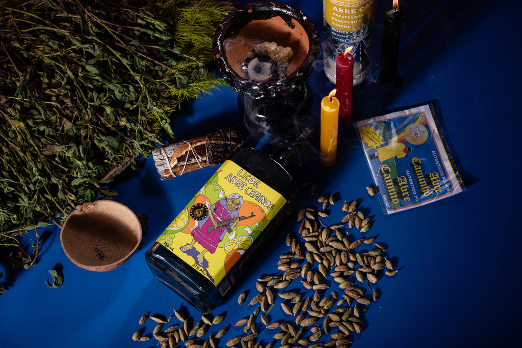 Licor abre caminos with colorful label on a blue surface with ingredients including a candle and esoteric vibe